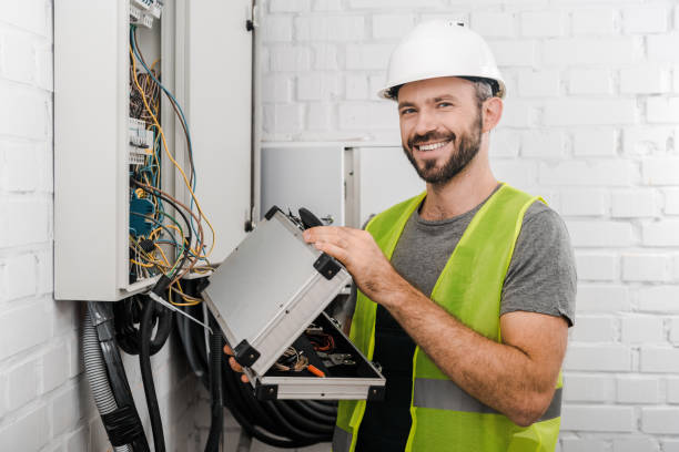 istock smiling electrician holding toolbox near electrical box in corridor and looking at camera 1049771432