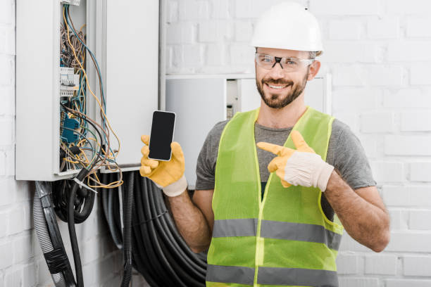 istock smiling handsome electrician pointing on smartphone with blank screen near electrical box in corridor 1049775286