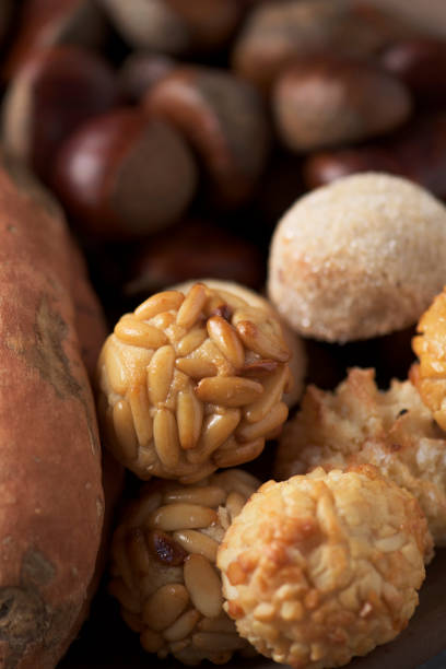 closeup of some chestnuts, some panellets and a roasted sweet potato, as a typical snack eaten in All Saints Day in Catalonia, Spain, called castanada