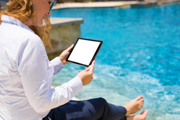 istock Business woman using tablet computer by the pool 1049784700