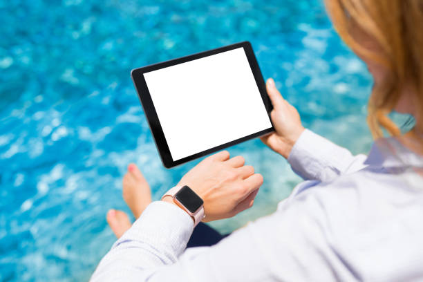istock Woman using modern technology gadgets on vacation by the pool 1049784776