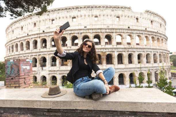 femme souriante tenant selfie devant le colisée - international landmark italy amphitheater ancient photos et images de collection