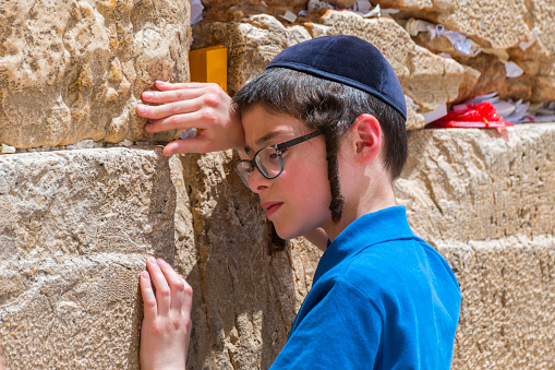 Young boy praying at the Western wall in Jerusalem old city, Israel.