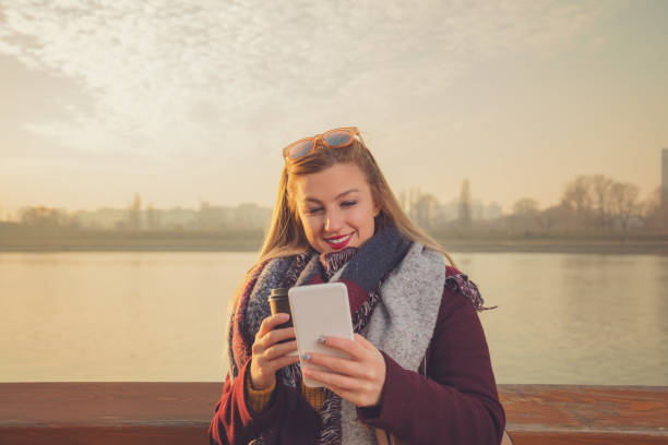 istock Beautiful woman using cellphone and drinking coffee outdoors. 1049787770