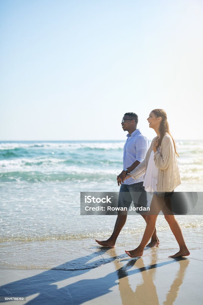 Fresh air does wonders for their relationship Shot of a young couple taking a stroll along the beach 20-29 Years Stock Photo