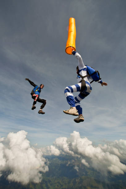 os para-quedistas mergulham através de sublimes céus acima de área rural - skydiving parachute parachuting taking the plunge - fotografias e filmes do acervo