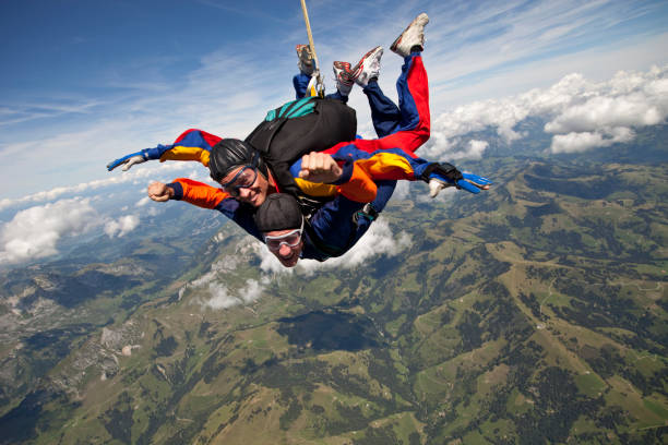 タンデム スカイダイバー山上空の高尚なを介して突入します。 - skydiving parachute parachuting taking the plunge ストックフォトと画像