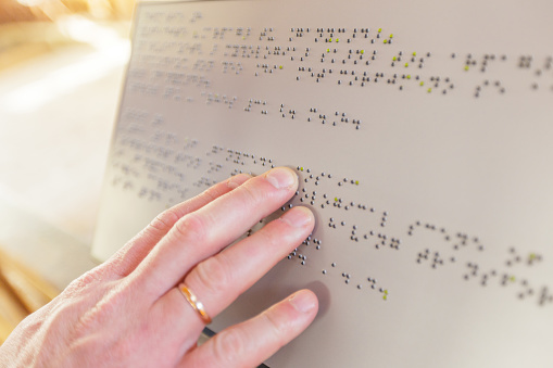 Hand of a blind person reading some braille text touching the relief.
