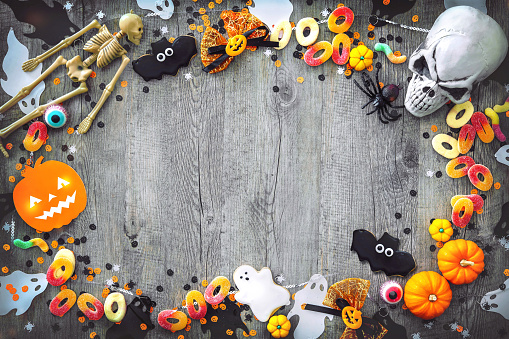 Halloween holiday background with skull, skeleton, spiders, pumpkins and candy. View from above
