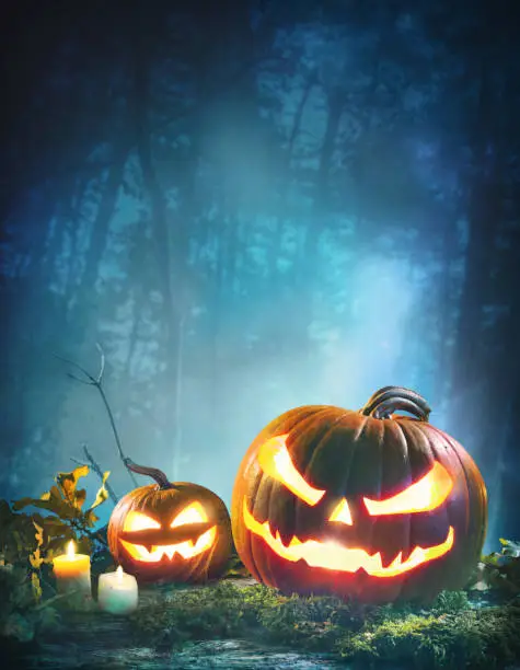 Photo of Jack oâ lanterns glowing at moonlight in front of spooky forest