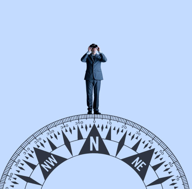 istock Businessman With Binoculars Standing On Top Of Compass 1049812752