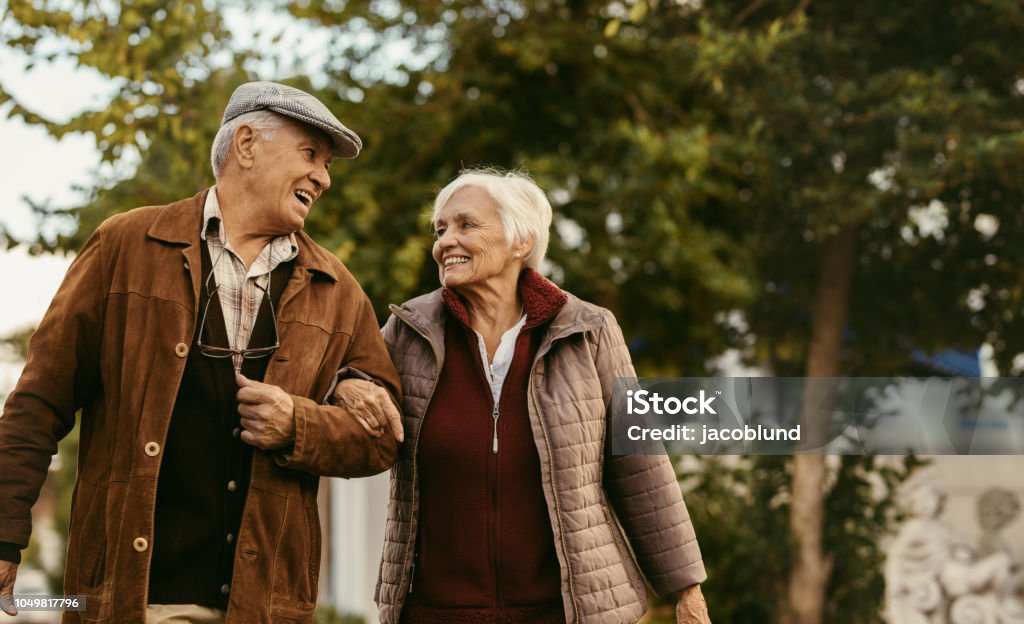 Loving senior couple enjoy a walk together on a winter day Portrait of happy retired man and woman in warm clothing walking outdoors on street. Loving senior couple enjoy a walk together on a winter day. Senior Adult Stock Photo