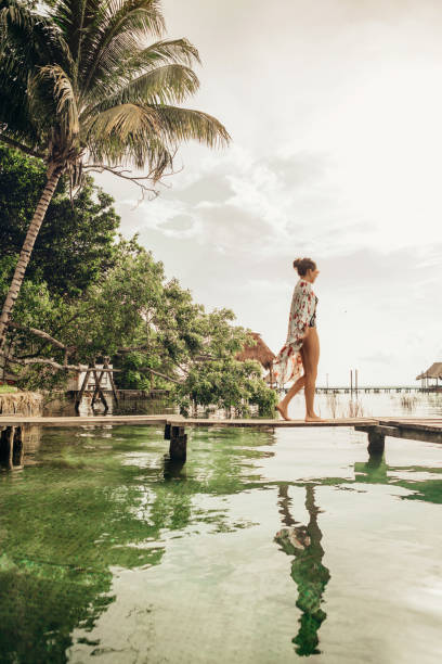 frau zu fuß auf einem pier an einer lagune - travel to mexico stock-fotos und bilder