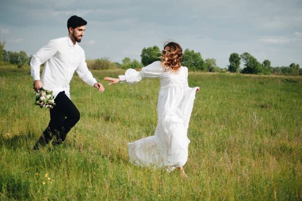 istock Couple Walking On Grassy Field Against Sky 1049820886