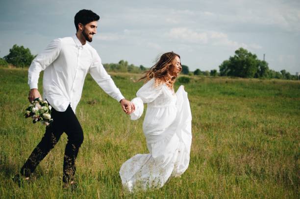 istock Couple Walking On Grassy Field Against Sky 1049820888