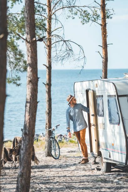 istock handsome man in hat in camp with trailer and bicycle 1049824850
