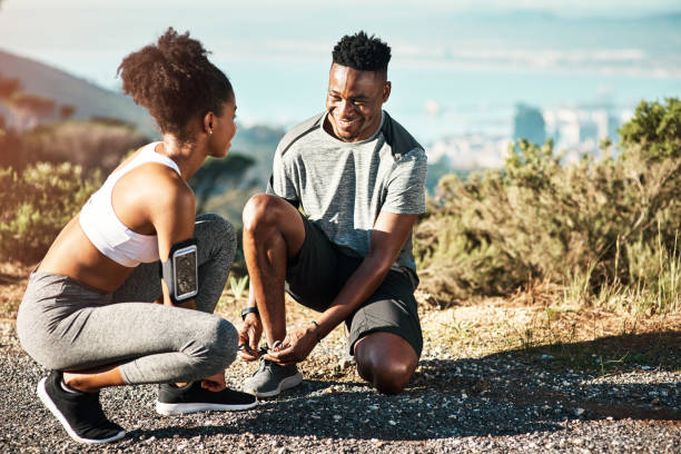 I don't want anything to interfere with this workout Full length shot of a young couple fastening their shoelaces before beginning their run lace fastener photos stock pictures, royalty-free photos & images