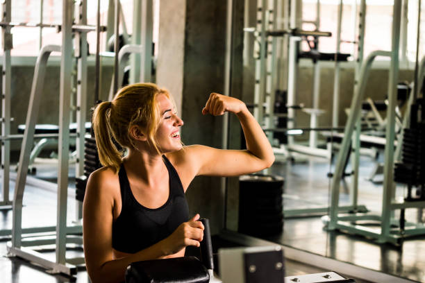 istock Attractive young woman showing her muscles while exercise at the gym 1049836810
