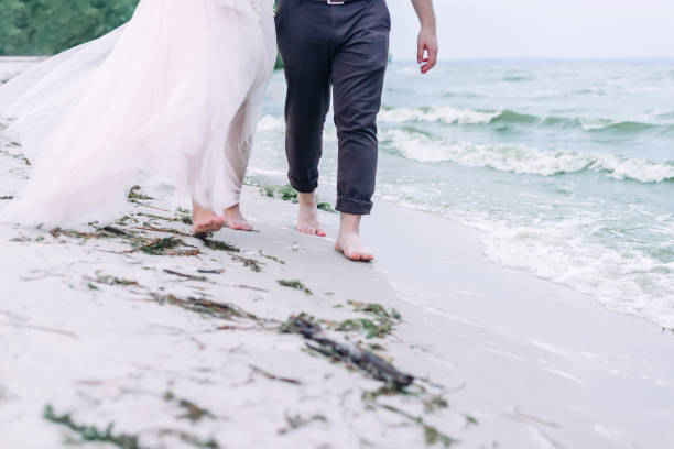 couple de mariage marche pieds nus sur la plage de sable. - elope photos et images de collection