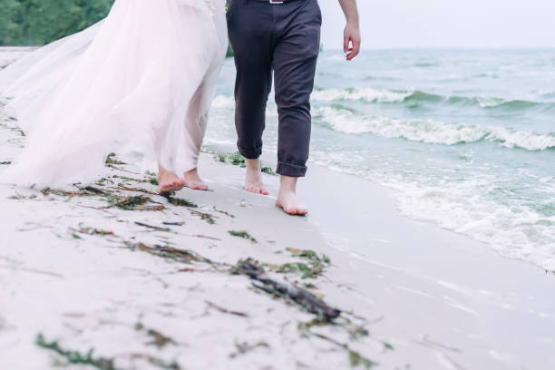 Wedding couple walking barefoot on the sand beach. Wedding couple walking barefoot on the sand beach. Cropped. eloping stock pictures, royalty-free photos & images