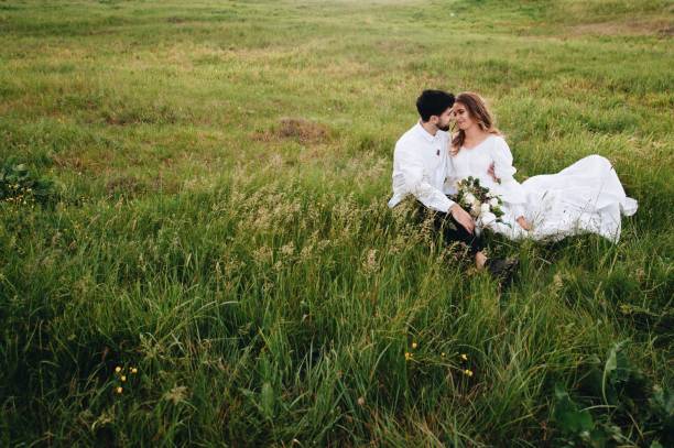 istock Bride And Bridegroom Sitting On Grassy Field 1049848454