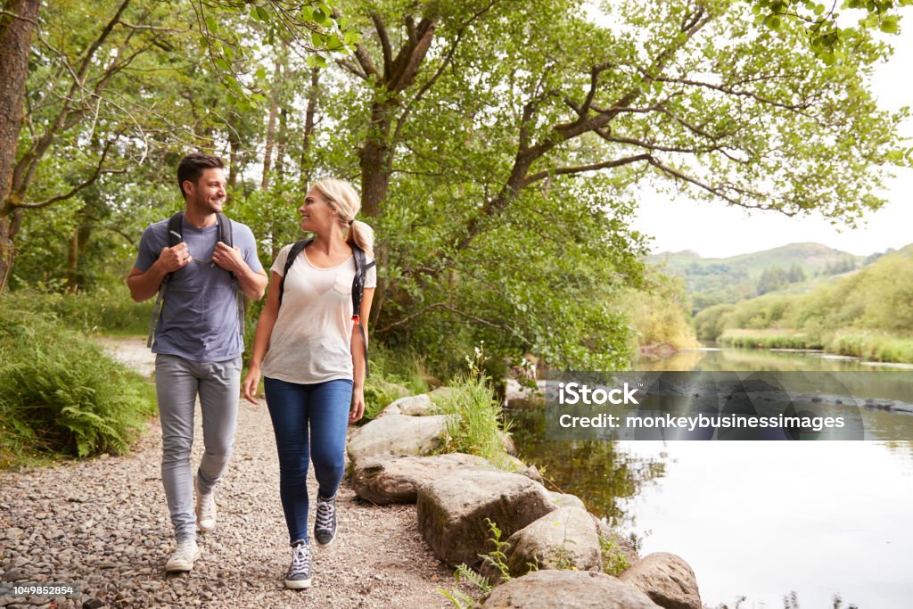 Couple Hiking Along Path By River In UK Lake District Walking Stock Photo
