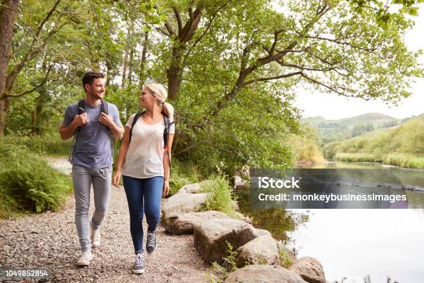 Couple Hiking Along Path By River In Uk Lake District Stock Photo - Download Image Now