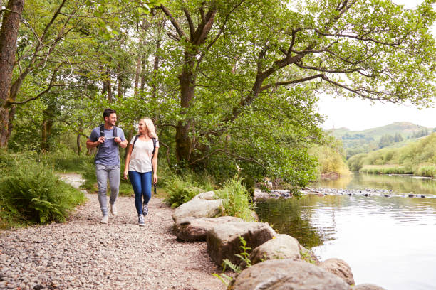 istock Couple Hiking Along Path By River In UK Lake District 1049852858