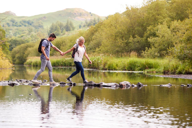 英国湖地区にはハイキングしながらカップルの交差の川 - river crossing ストックフォトと画像