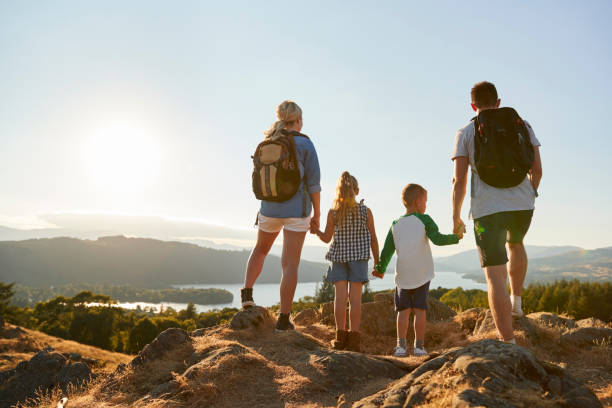 vue arrière de famille debout au sommet de la colline sur la randonnée à travers la campagne à lake district uk - parc national photos et images de collection