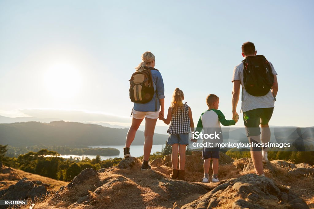 Rear View Of Family Standing At Top Of Hill On Hike Through Countryside In Lake District UK Family Stock Photo