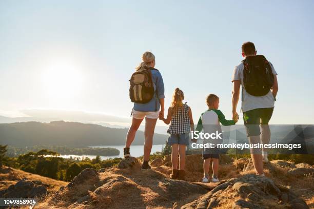 Rear View Of Family Standing At Top Of Hill On Hike Through Countryside In Lake District Uk Stock Photo - Download Image Now