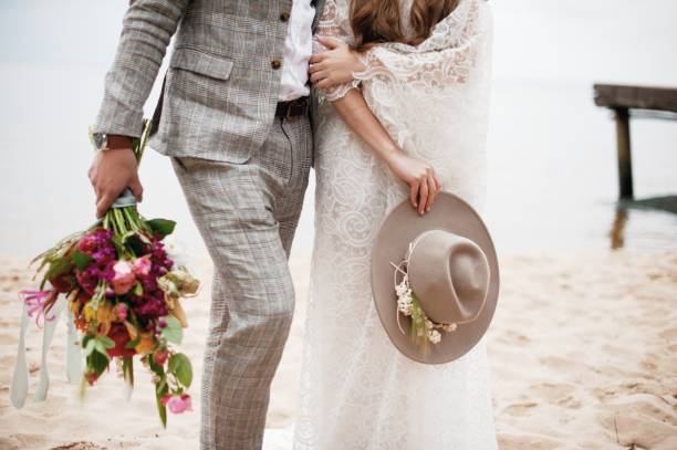 istock Midsection Of Bride And Bridegroom Standing At Beach 1049863024