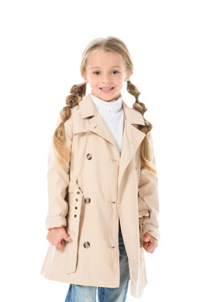 istock adorable smiling kid posing in beige autumn coat, isolated on white 1049863228