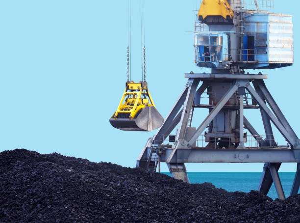 roboczy dźwig portowy i wiadro, załadunek węgla. morski terminal załadunkowy, port handlowy.  żuraw chwytak i stos węgla kamiennego przed morzem i błękitnym niebem - coal crane transportation cargo container zdjęcia i obrazy z banku zdjęć