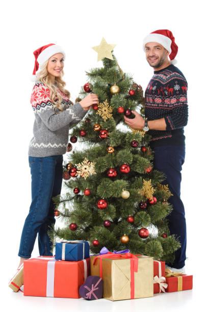 istock beautiful couple decorating christmas tree with gift boxes, isolated on white 1049876804