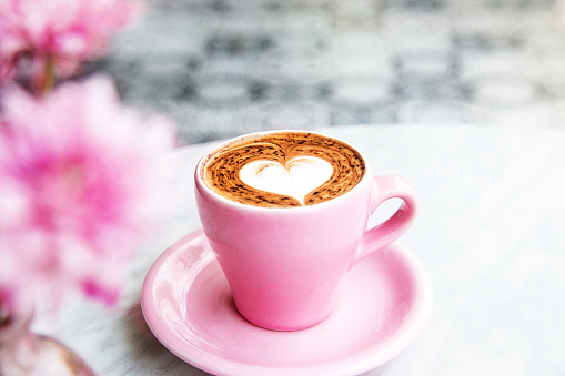 Pink Cup of hot latte coffee on marble table background with art floor on the background