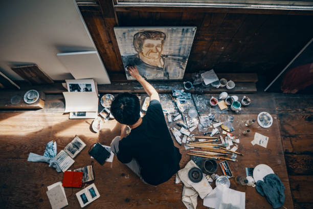 Mature man painting with oil paint in his studio Mature man sitting on the floor painting with oil paint in his studio workshop art studio art paint stock pictures, royalty-free photos & images