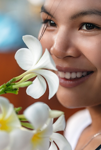 Beautiful young asian woman smelling frangipani