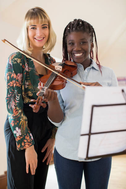 portret nauczycielki w szkole średniej z uczniem grającym na skrzypcach w lekcji muzyki - practicing music violin women zdjęcia i obrazy z banku zdjęć