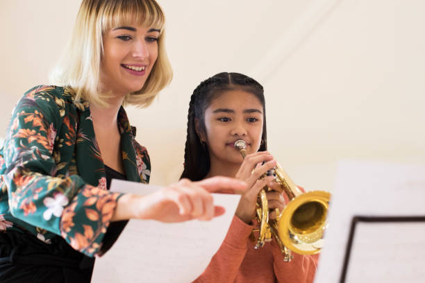 lehrer helfen, studentin im musikunterricht trompete - music lessons stock-fotos und bilder