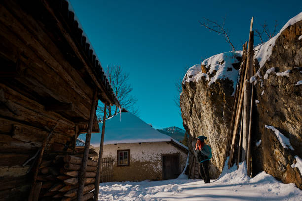 side view of young woman near wooden chalet relaxing and berathing fresh air.