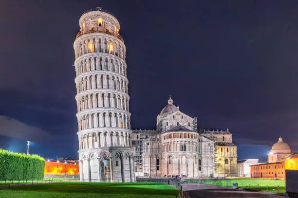 World heritage Pisa tower, baptistery and cathedral at night. Famous tourist attraction, symbol of Italy