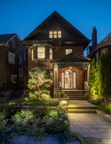 Luxury urban Home exterior at night Toronto, Canada - September 23, 2018. Night  time Front facade of luxury urban home with proper landscaped front lawn and entrance. Front entrance door open showing luxury interior with art work on the walls. With all interior lights powered on, the rest of the window view discloses the rest of modern luxury interior. looking out front door stock pictures, royalty-free photos & images