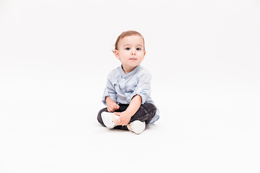 Happy baby boy is sitting on white background, studio shot