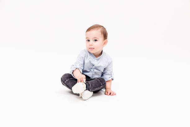 istock Happy baby boy is sitting on white background 1049898038
