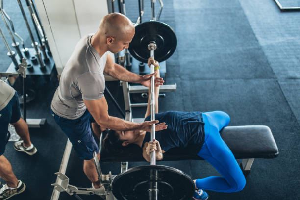 istock Trainer helping girl in gym 1049929366