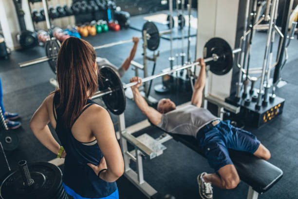 allenatore che mostra l'esercizio fisico a una donna - women weight bench exercising weightlifting foto e immagini stock