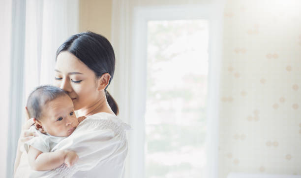 close up portrait of beautiful young asian mother kissing her newborn baby. - mother baby new kissing imagens e fotografias de stock