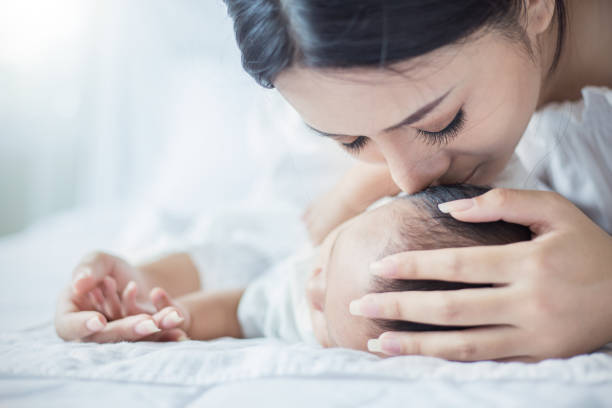 close up portrait of beautiful young asian mother kissing her newborn baby. - mother baby new kissing imagens e fotografias de stock